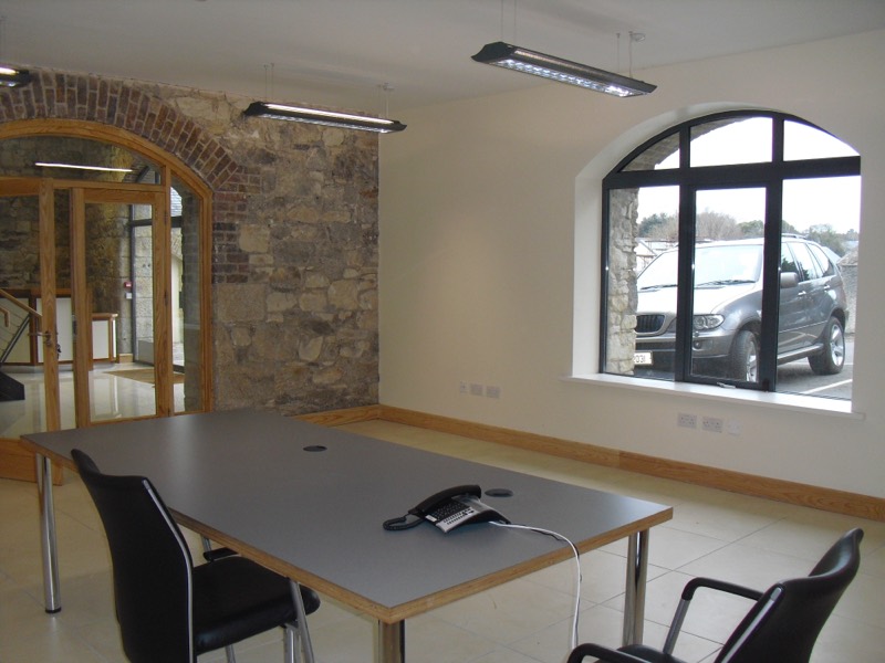 The conference room: brick arch, exposed stone wall and an arched window onto the car park
