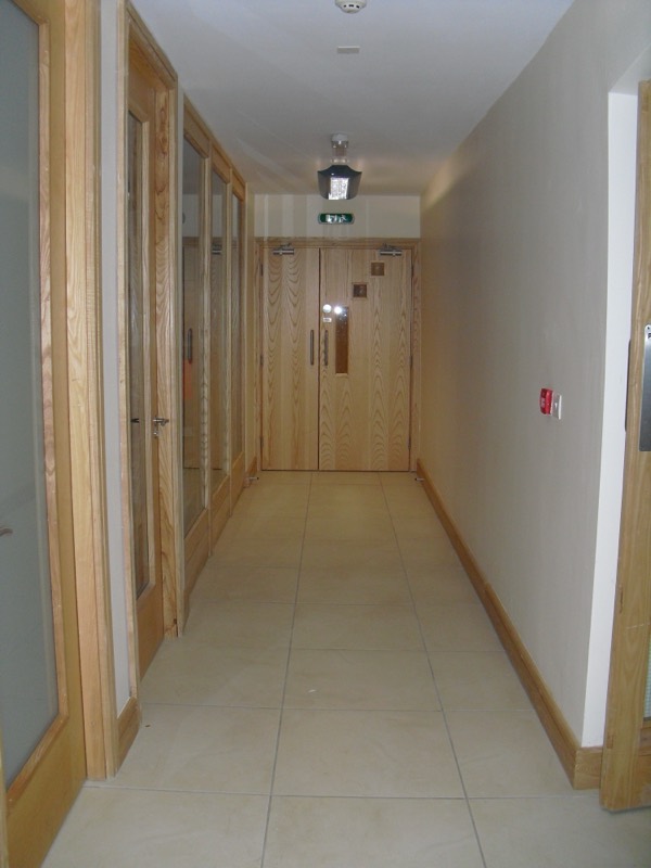 A first-floor corridor lined with oak-and-glass office fronts
