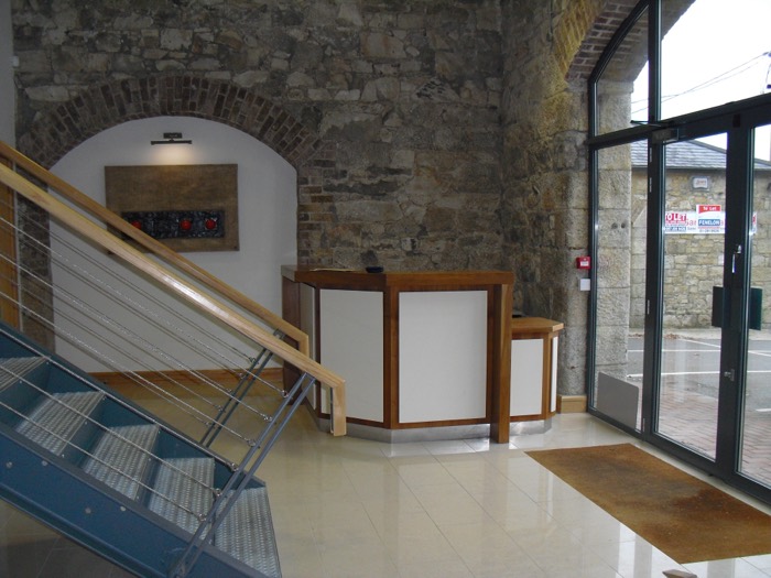 The reception desk beneath a whitewashed brick arch beside the glazed entrance