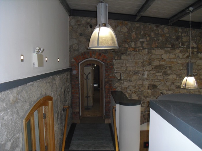 Original granite and rubble-stone walls under industrial pendant lamps